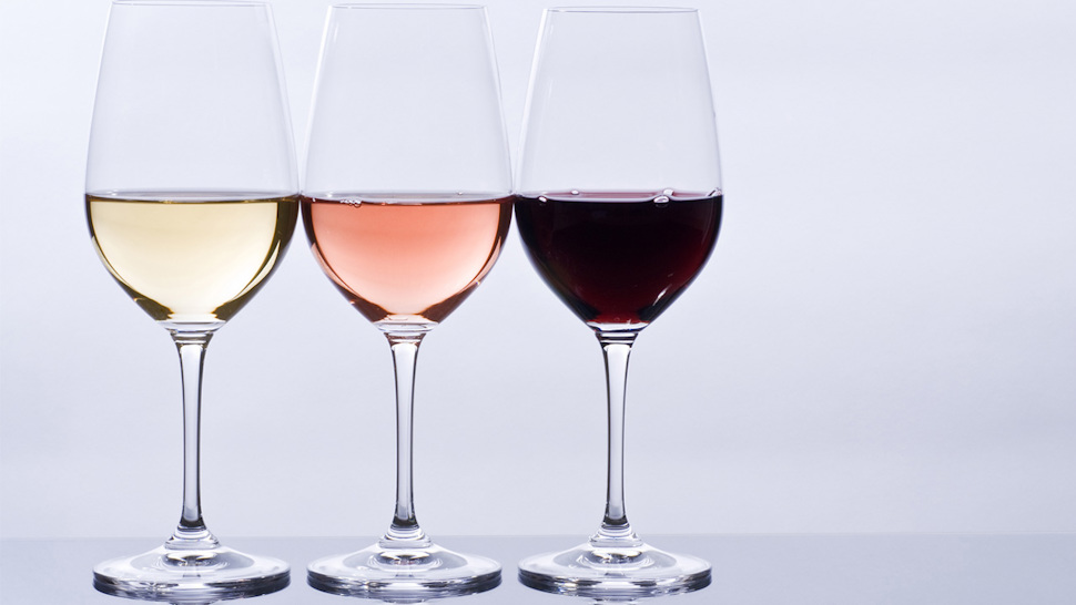 Three wine glasses with white rose and red wines